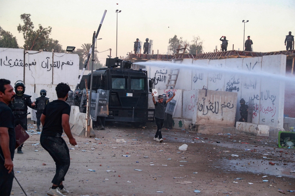 Iraqi riot police use water cannon to disperse supporters of Iraqi Shiite cleric Moqtada al-Sadr gathering for a protest outside the Swedish embassy in Baghdad on July 20, 2023. Photo by Ahmad AL-RUBAYE / AFP