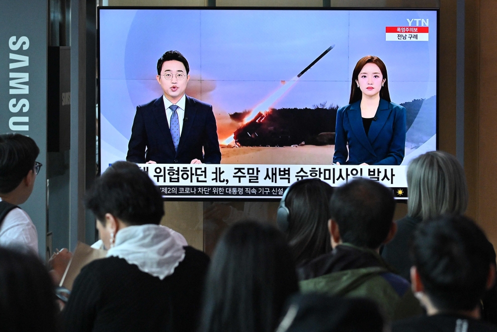 People watch a television screen showing a news broadcast with file footage of a North Korean missile test, at a railway station in Seoul on July 22, 2023. (Photo by Jung Yeon-je / AFP)