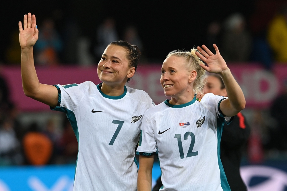 New Zealand's defender #07 Ali Riley (L) and New Zealand's midfielder #12 Betsy Hassett (R) greet supporters at the end of Australia and New Zealand 2023 Women's World Cup Group A football match between Switzerland and New Zealand at Dunedin Stadium in Dunedin on July 30, 2023. (Photo by Sanka Vidanagama / AFP)