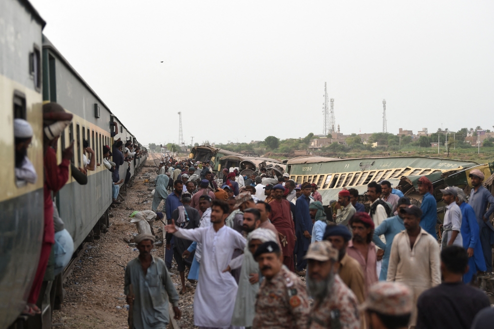 Railway workers repaire the tracks next to damaged carriages a day after the derailment of a passenger train in Nawab Shah on August 7, 2023. (Photo by Asif Hassan / AFP)