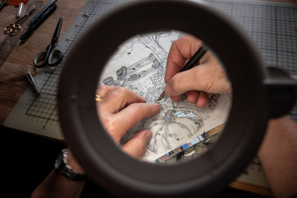 Swiss paper cutting artist Marianne Dubuis works on a piece at her home, in Chateau d'Oex, in the Prealps in western Switzerland on July 25, 2023. Photos by Fabrice COFFRINI / AFP