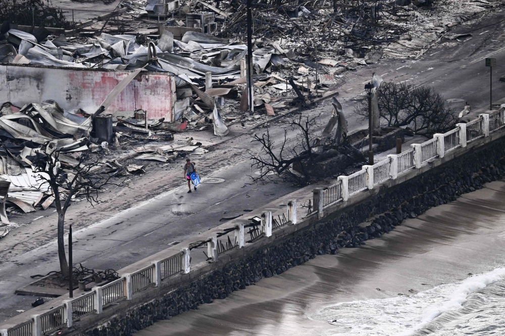 An aerial image taken on August 10, 2023 shows a person walking down Front Street past destroyed buildings burned to the ground in Lahaina in the aftermath of wildfires in western Maui, Hawaii. Photos by Patrick T. Fallon / AFP