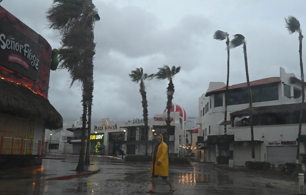A man walks along a street in Cabo San Lucas, Baja California State, Mexico, as rain and gusts of wind of Hurricane Hilary reach the area, on August 19, 2023. (Photo by Alfredo ESTRELLA / AFP)
