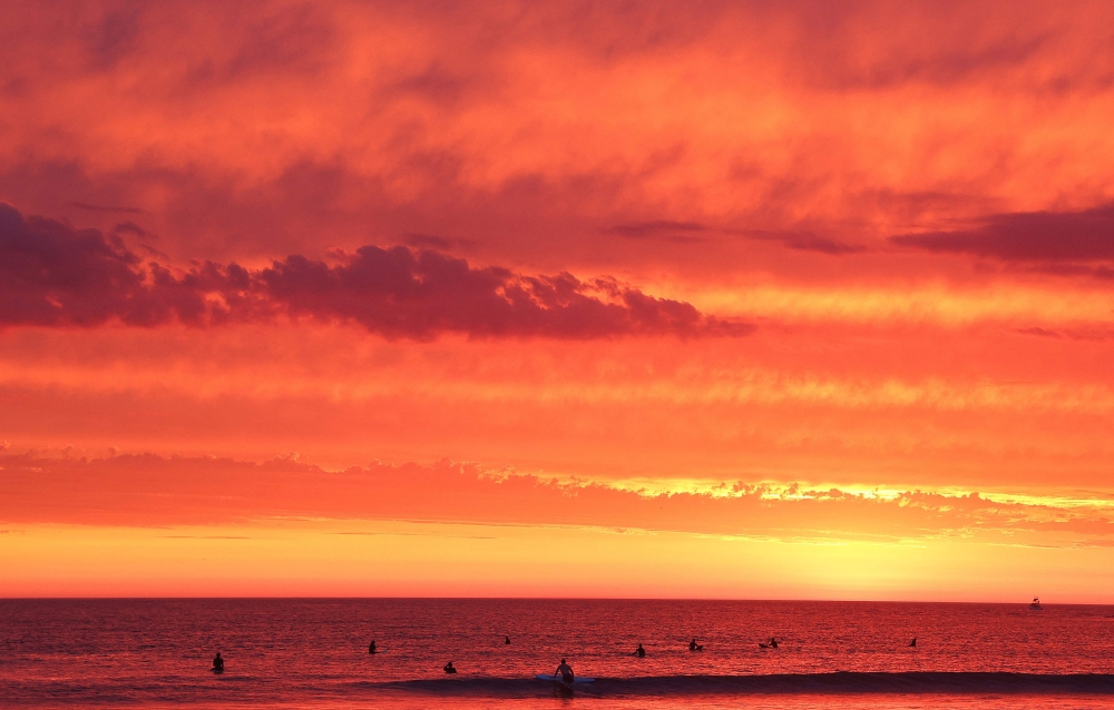People surf as clouds past shortly after sunset at Ocean Beach with Hurricane Hilary approaching on August 19, 2023 in San Diego, California. (Photo by MARIO TAMA / GETTY IMAGES NORTH AMERICA / Getty Images via AFP)
