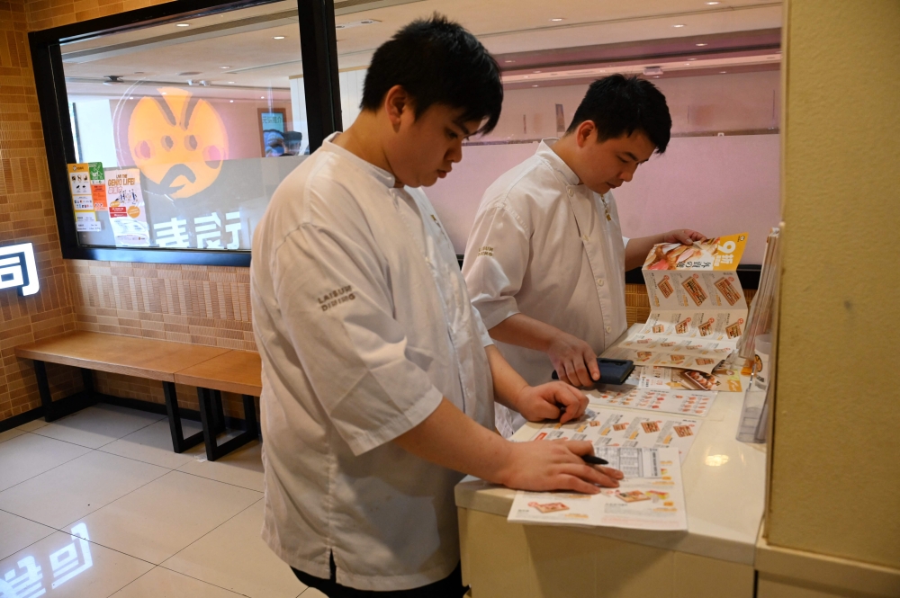 Customers look at the takeaway menu in a Japanese Sushi restaurant in Hong Kong on August 22, 2023. Photo by Peter PARKS / AFP