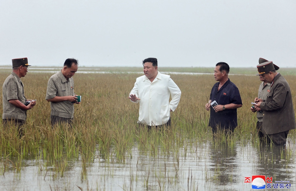 This picture taken on August 21, 2023 and released from North Korea's official Korean Central News Agency (KCNA) on August 22, 2023 shows North Korea's leader Kim Jong-un (centre) in waste-deep water as he visits the restoration site of reclaimed land which suffered flood damage due to the levee breaking in the western port city of Nampo. (Photo by KCNA VIA KNS / AFP)