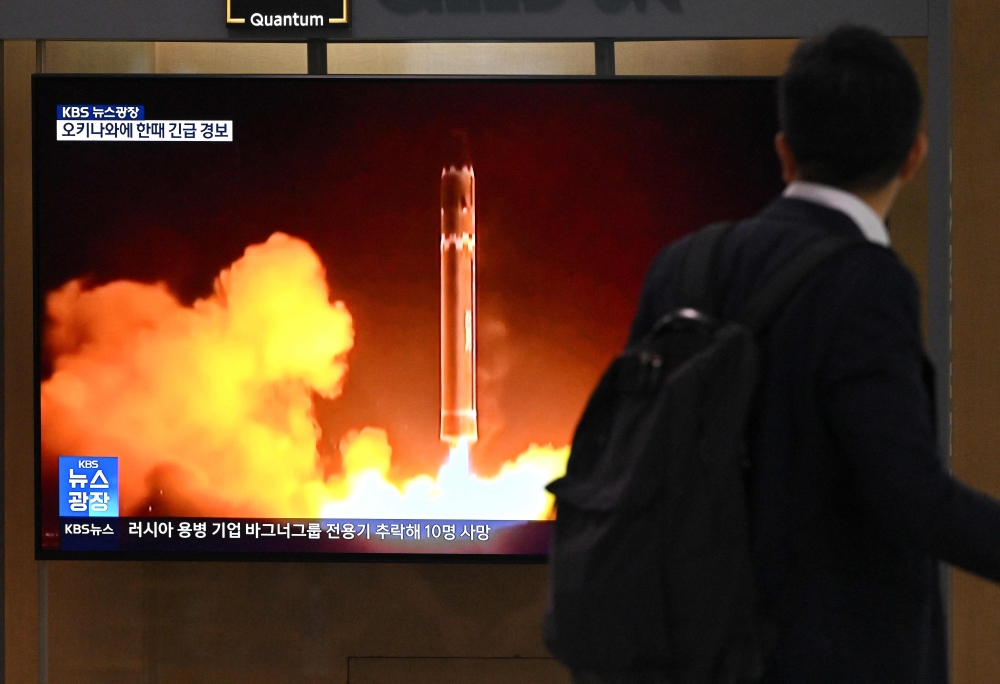 A man walks past a television screen showing a news broadcast with file footage of a North Korean missile test, at a railway station in Seoul on August 24, 2023. (Photo by Jung Yeon-je / AFP)
