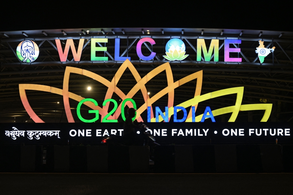 A man rides past an illuminated hoarding with the G20 logo displayed along a street in New Delhi on August 29, 2023. (Photo by Arun Sankar / AFP)

