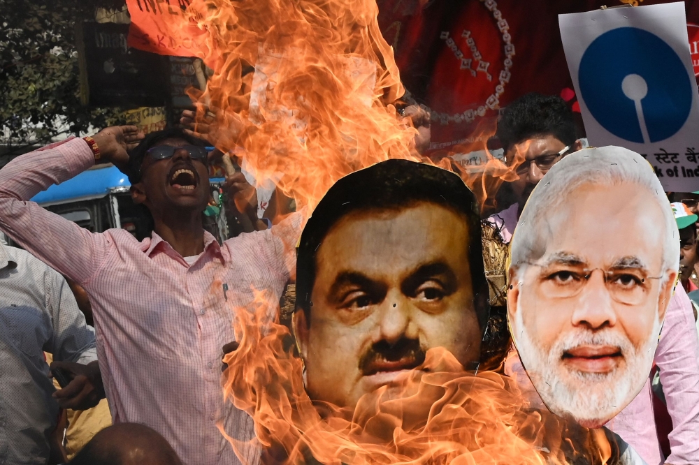 An activist of India's Congress party burns an effigy of Prime Minister Narendra Modi (right) and Indian tycoon Gautam Adani during a protest against financial policies in Kolkata on February 6, 2023. (Photo by Dibyangshu Sarkar / AFP)