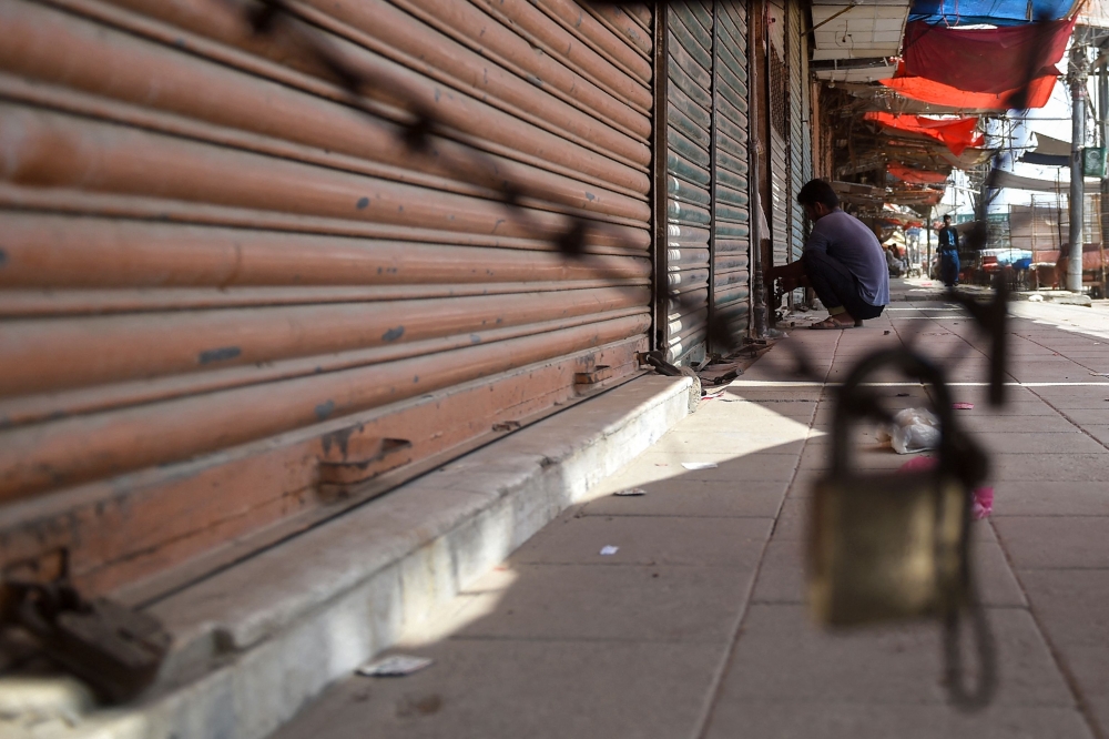 A shopkeeper locks a shop along a roadside in Karachi on September 2, 2023 (Photo by Rizwan Tabassum / AFP)