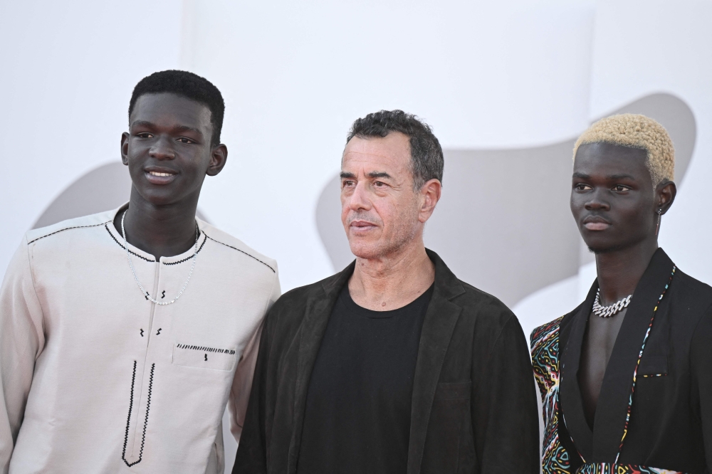 Actor Seydou Sarr (L), Italian director Matteo Garrone (C) and actor Moustapha Fall pose during the red carpet of the movie