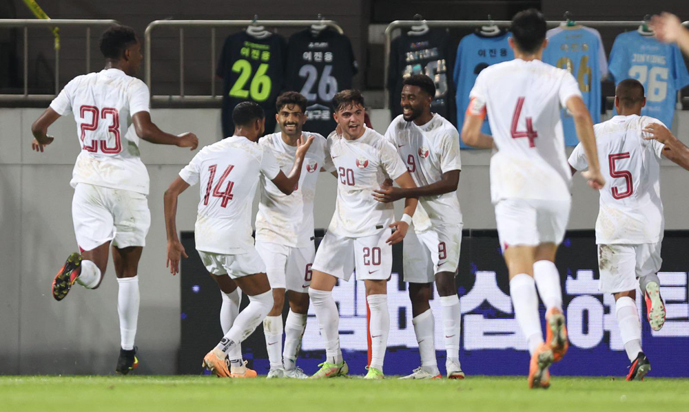 Ahmed Al Rawi (centre) celebrates with teammates after scoring Qatar's first goal.