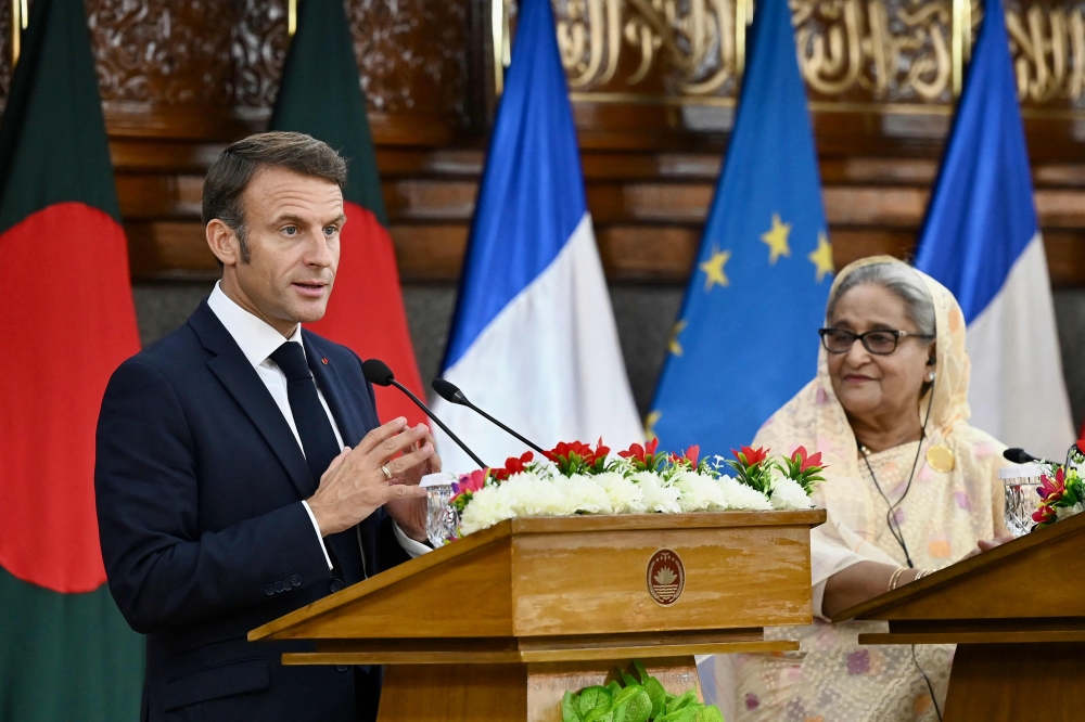 France's President Emmanuel Macron (L) speaks as Bangladesh's Prime Minister Sheikh Hasina looks on during the ceremony of signing bilateral agreements at the Prime Minister's office in Dhaka on September 11, 2023. (Photo by Munir uz zaman / AFP)