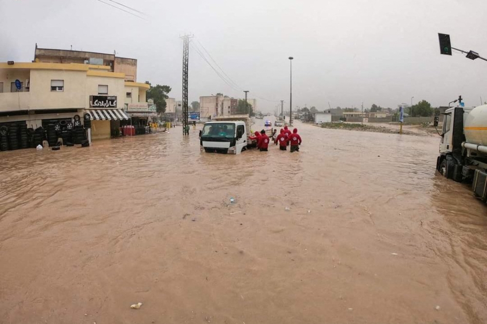This picture released by the Libyan Red Crescent on September 11, 2023, shows members of their team working on opening roads engulfed in floods at an undefined location in eastern Libya. (Photo by Libyan Red Crescent / AFP) 