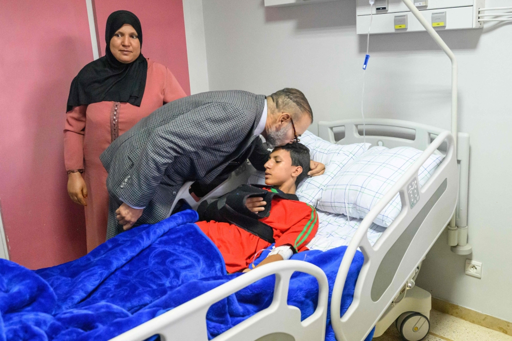 This handout picture taken and released on September 12, 2023 shows Moroccan King Mohammed VI kissing the head of an injured victim at “Mohammed VI” University Hospital in Marrakech, as he pays a hospital visit to victims of the earthquake that rocked the North African country last wee. (Photo by Moroccan Royal Palace / AFP) 