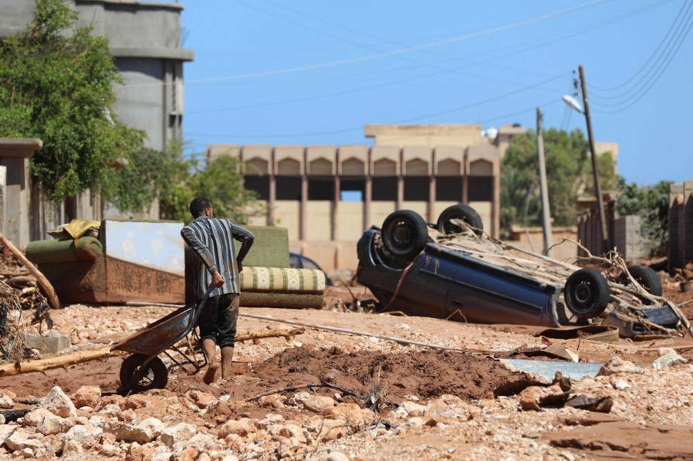 A man crosses the rubble filled street in Libya's eastern city of Soussa on September 15, 2023,  Photo by Mohamed Shalash / AFP
