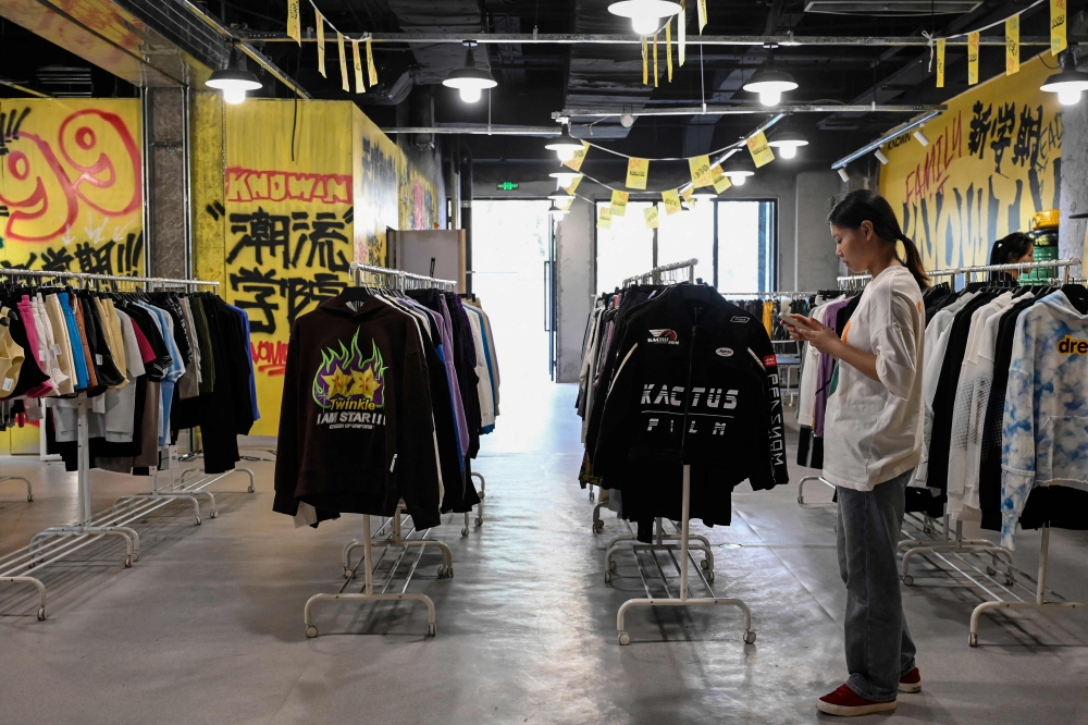 (Files) A salesperson waits for customers at a clothing shop at a shopping mall in Beijing on September 7, 2023. (Photo by Jade GAO / AFP)