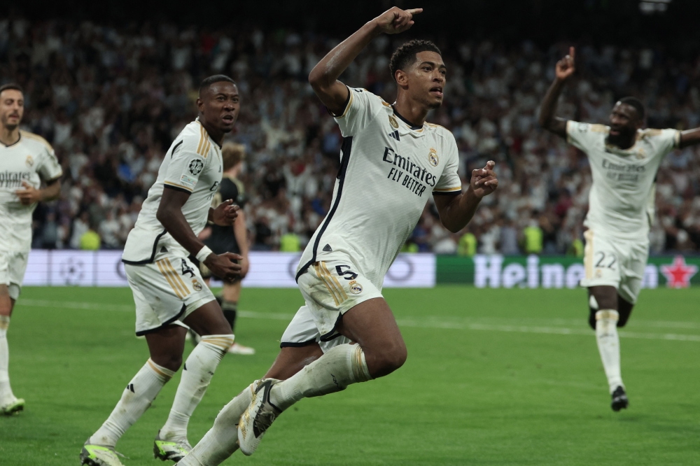 Real Madrid's English midfielder #5 Jude Bellingham celebrates with teammates scoring his team's first goal during the UEFA Champions League 1st round day 1 group C football match between Real Madrid and Union Berlin at the Santiago Bernabeu stadium in Madrid on September 20, 2023. (Photo by Thomas COEX / AFP)
