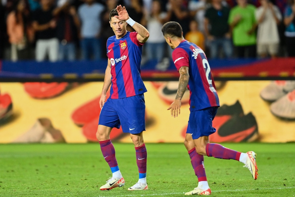 Barcelona's Portuguese defender #02 Joao Cancelo celebrates with Barcelona's Polish forward #09 Robert Lewandowski after scoring his team's third goal during the Spanish Liga football match between FC Barcelona and RC Celta de Vigo at the at the Estadi Olimpic Lluis Companys in Barcelona on September 23, 2023. (Photo by Pau BARRENA / AFP)
