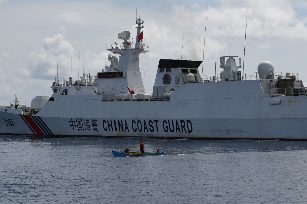 This photo taken on September 22, 2023 shows a wooden boat, with Philippine fisherman Arnel Satam on board, drawfed by a Chinese coast guard vessel after he was intercepted for attempting to enter Scarborough Shoal in disputed waters of the South China Sea. (Photo by Ted Aljibe / AFP)