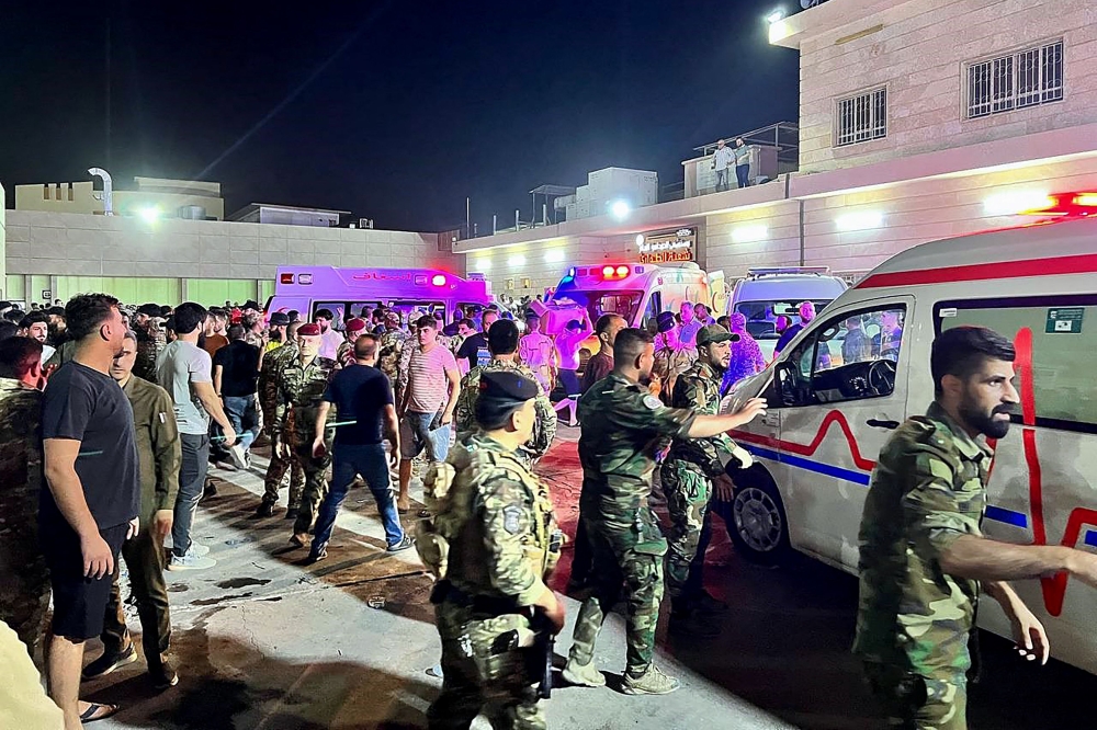 Soldiers and emergency responders gather around ambulances carrying wounded people after a fire broke out during a wedding at an event hall, outside the Hamdaniyah general hospital in Al-Hamdaniyah, Iraq on September 27, 2023. (Photo by Zaid Al-Obeidi / AFP)