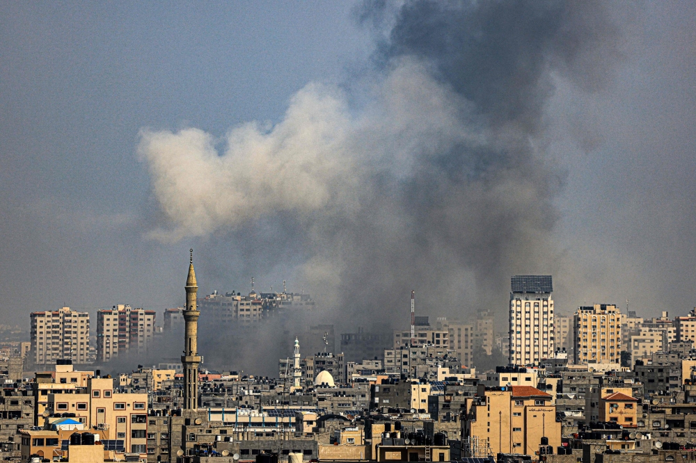 A plume of smoke rises above buildings in Gaza City during an Israeli air strike, on October 8, 2023. (Photo by Mahmud Hams / AFP)