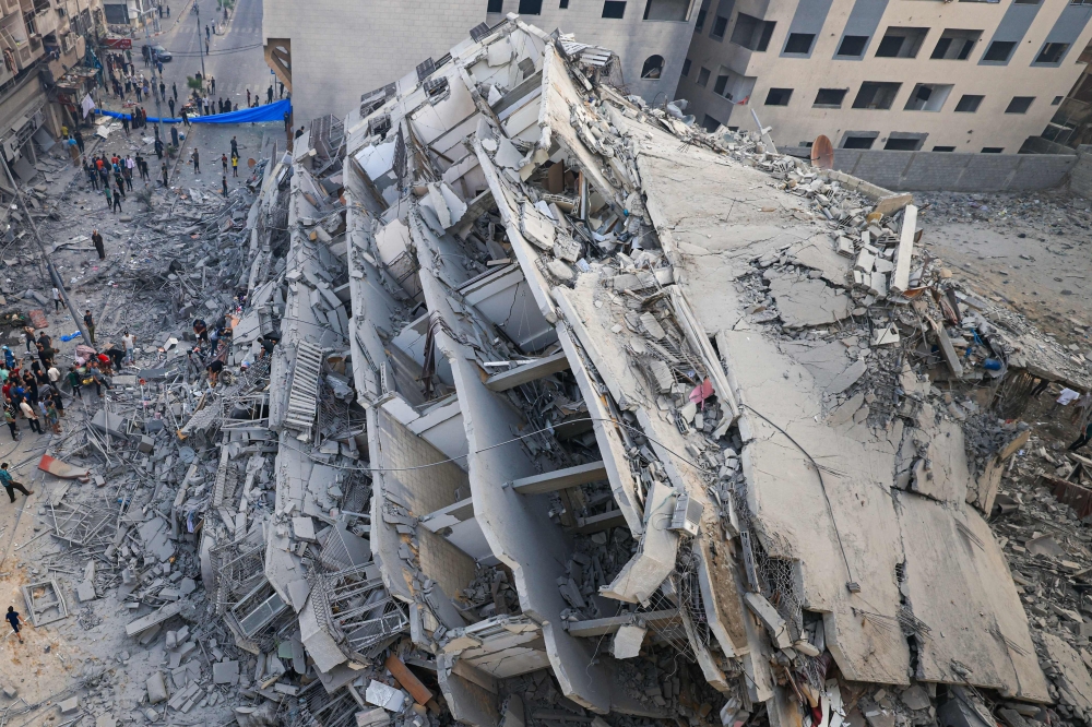 People inspect the ruins of a building destroyed in Israeli strikes in Gaza City on October 8, 2023. (Photo by Mahmud Hams / AFP)