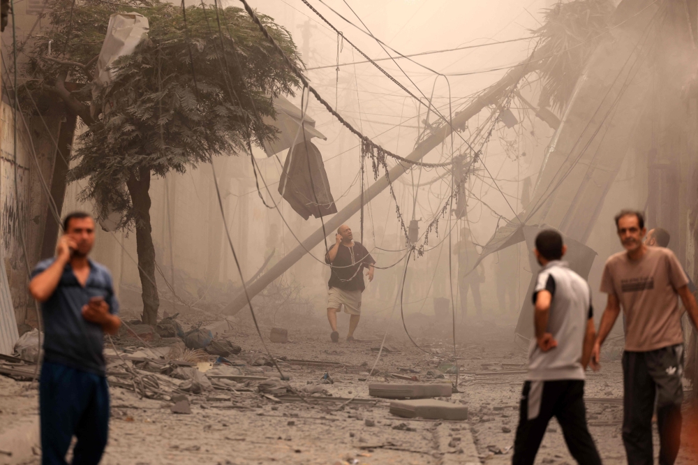 Palestinians inspect the destruction in a neighbourhood heavily damaged by Israeli airstrikes on Gaza City's Shati refugee camp early on October 9, 2023. (Photo by Mahmud Hams / AFP)
