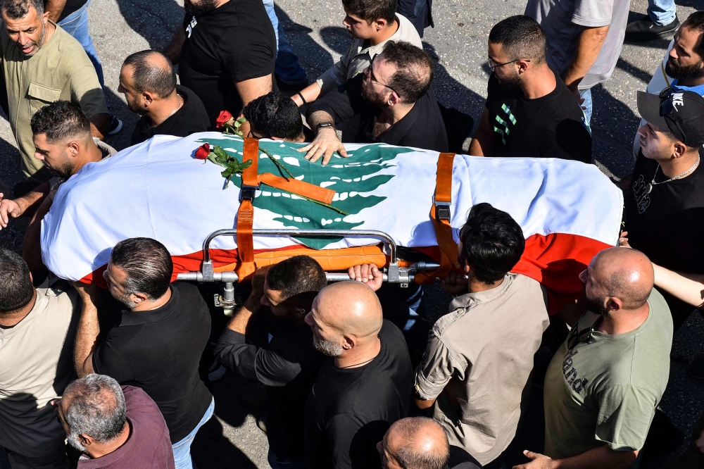 Mourners carry the casket of Lebanese Reuters video journalist Issam Abdallah, killed on October 13 by Israeli shelling at Alma al-Shaab border village with Israel while covering cross border shelling, during his funeral in the village of El-Khiam on October 14, 2023. (Photo by Fadel ITANI / AFP)

