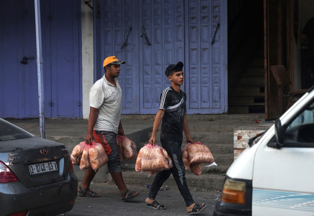 Men carry bags of bread in the Rafah refugee camp, in the southern of Gaza Strip on Octobers 15, 2023, as fighting between Israel and the Hamas movement continues, with Israel cutting off water, fuel and food supplies into the enclave. Photo by MOHAMMED ABED / AFP