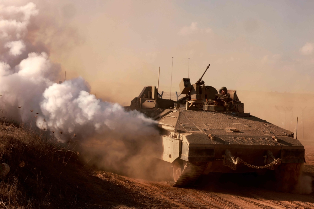 An Israeli armoured personnel carrier drives on a road at an undisclosed location on the border with the Gaza Strip on October 15, 2023. (Photo by Menahem Kahana / AFP)