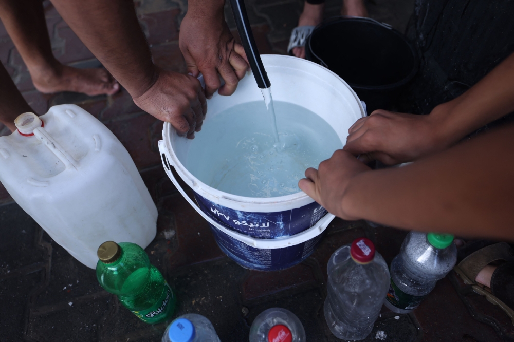 Palestinians queue for water at the Rafah refugee camp, in the southern Gaza Strip on October 17, 2023. (Photo by Mohammed Abed/ AFP)