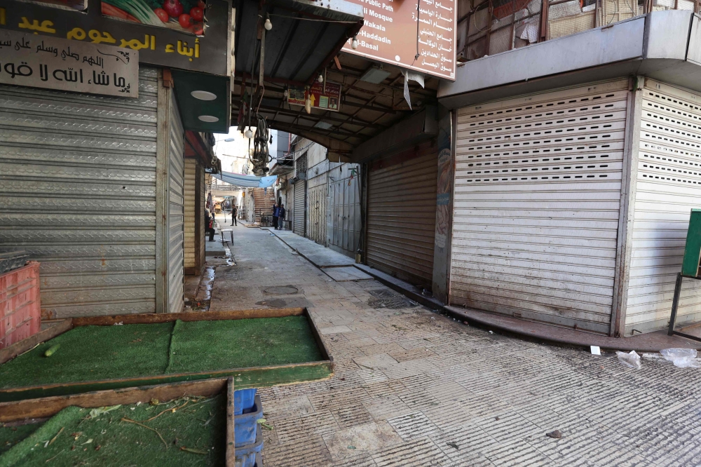 Palestinian youths stand in front of shuttered shops during a general strike in Nablus in the occupied West Bank, on October 18, 2023, a day after a rocket hit a Gaza hospital killing hundreds. (Photo by Zain JAAFAR / AFP)