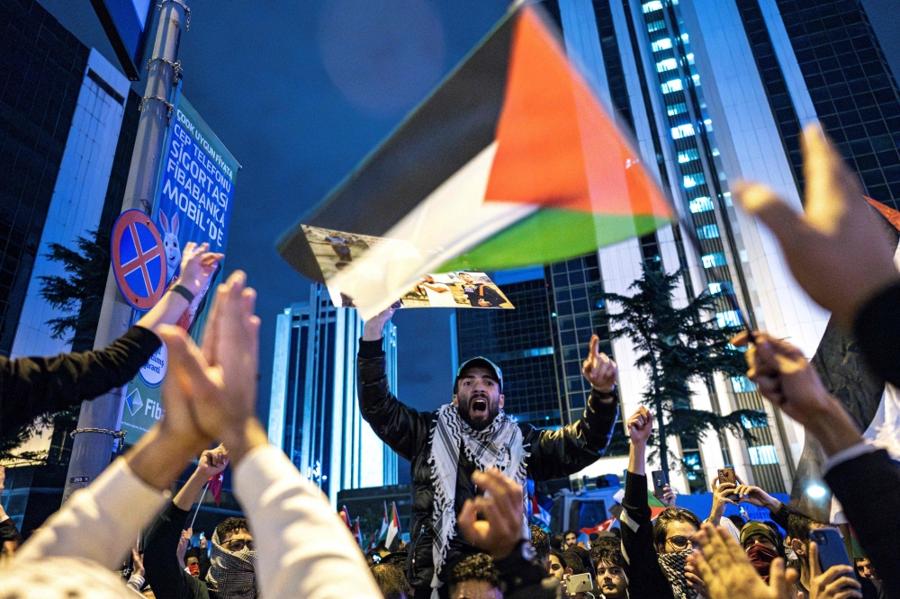 Protesters shout slogans and wave a Palestinian flag during a rally in support of Palestinians in Istanbul on October 18, 2023. (Photo by Umit Turhan Coskun / AFP)


