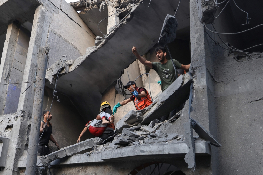 Palestinian civil defence members and others carry a child killed in an Israeli bombardment from a building in Khan Yunis on the southern Gaza Strip on October 19, 2023. Photo by Mahmud HAMS / AFP