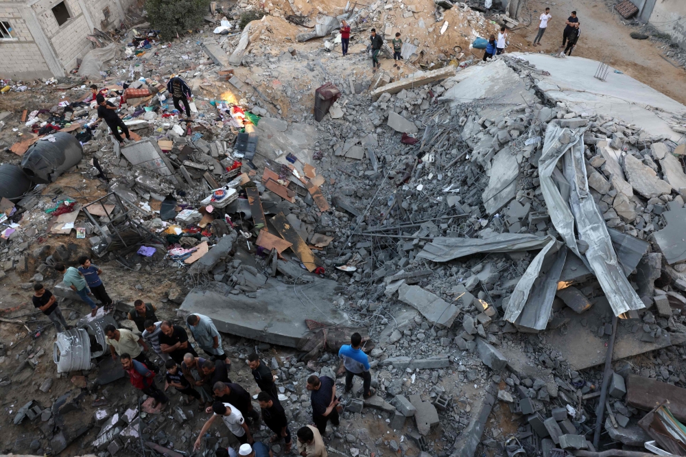 People check the rubble of a building destroyed in an Israeli bombardment in Rafah in the southern Gaza Strip on October 21, 2023. (Photo by Mohammed Abed / AFP)