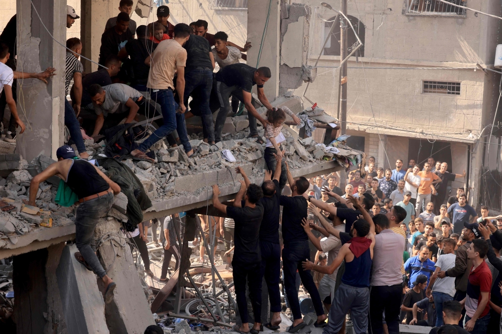 Rescuers pull a child out of the rubble of a building hit in an Israeli air strike in Khan Yunis in the southern Gaza Strip on October 24, 2023. (Photo by Mahmud Hams / AFP)