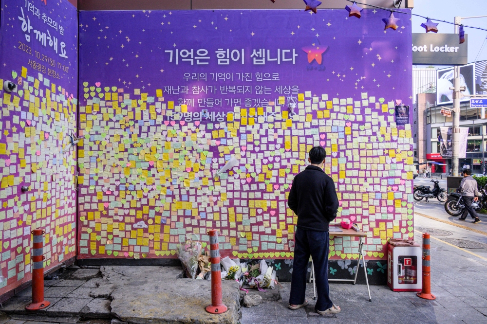 A man looks at flowers and notes left in memory of victims at the site of the October 29, 2022 crowd crush that killed more than 150 people during Halloween celebrations, in the popular Itaewon nightlife area in Seoul on October 25, 2023. Photo by ANTHONY WALLACE / AFP