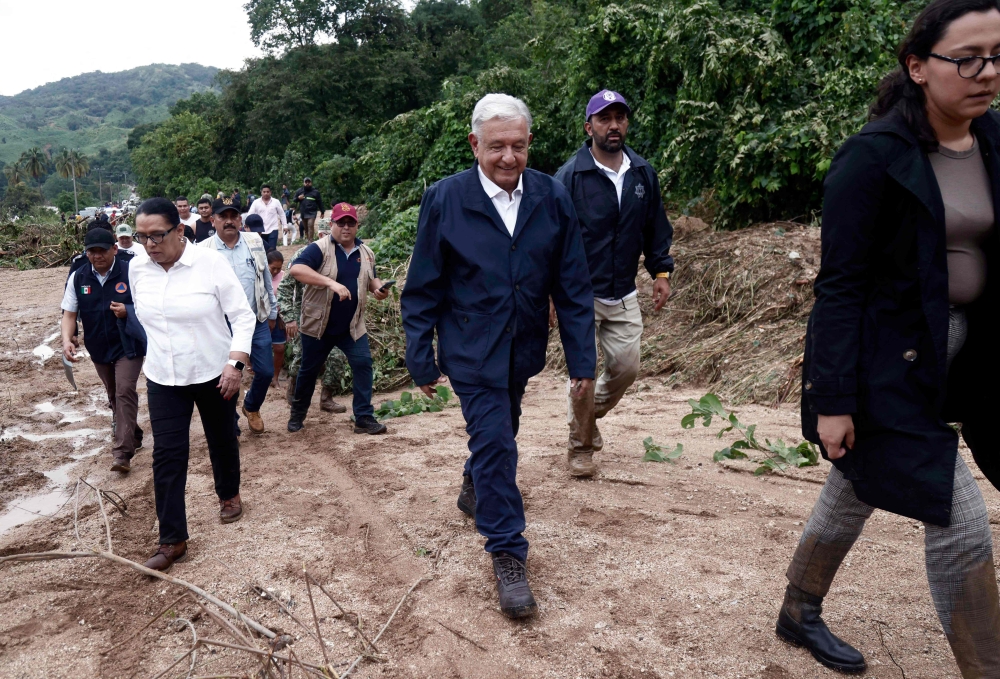 Mexican President Andres Manuel Lopez Obrador (C) and members of his cabinet walk amid debris as they visit the Kilometro 42 community, near Acapulco, Guerrero State, Mexico, after the passage of Hurricane Otis, on October 25, 2023. Photo by Rodrigo OROPEZA / AFP