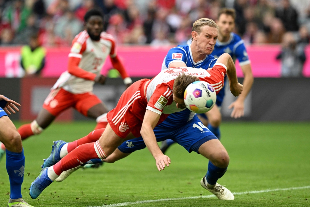 Bayern Munich's English midfielder Harry Kane heads the first goal for Munich against Darmstadt's Austrian defender #14 Christoph Klarer during the German first division Bundesliga football match between FC Bayern Munich and SV Darmstadt 98 in Munich, southern Germany on October 28, 2023. (Photo by Christof Stache / AFP)