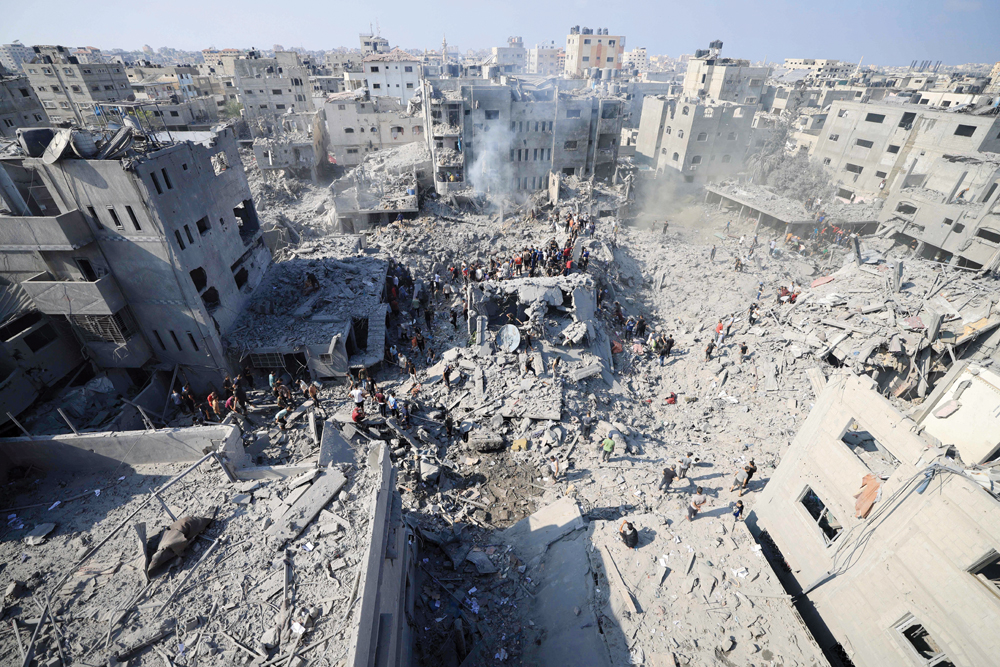 People check the rubble of buildings destroyed in an Israeli strike on the Bureij refugee camp in the central Gaza Strip yesterday. (AFP)