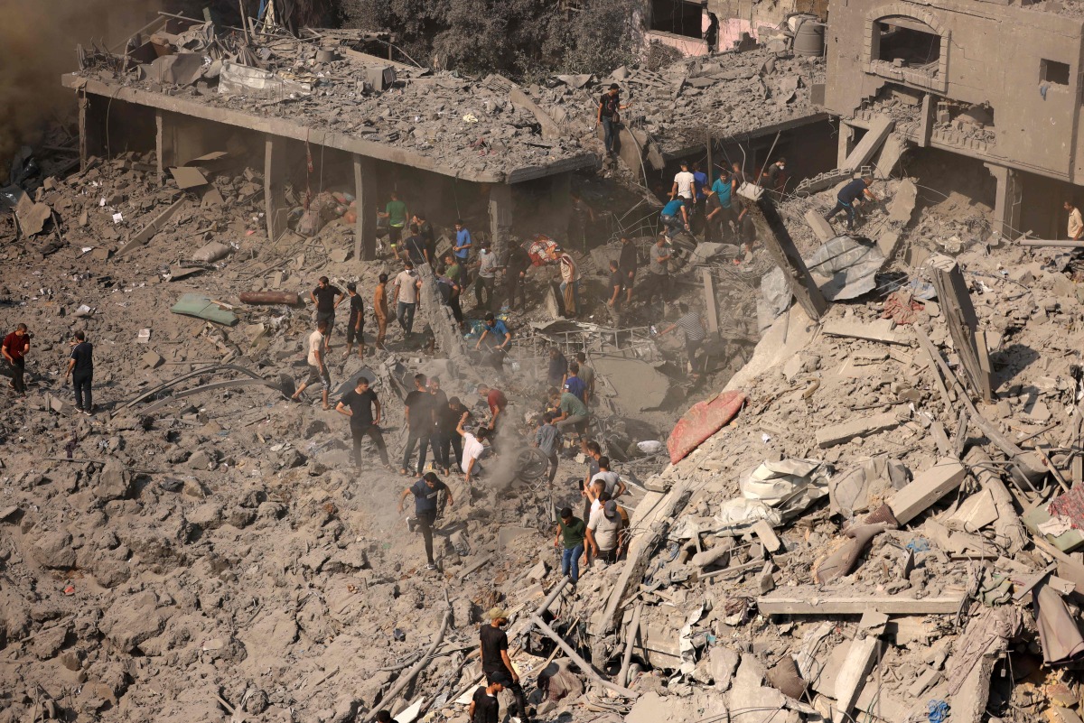 People check buildings destroyed in an Israeli strike on the Bureij refugee camp in the central Gaza Strip yesterday. (AFP)
