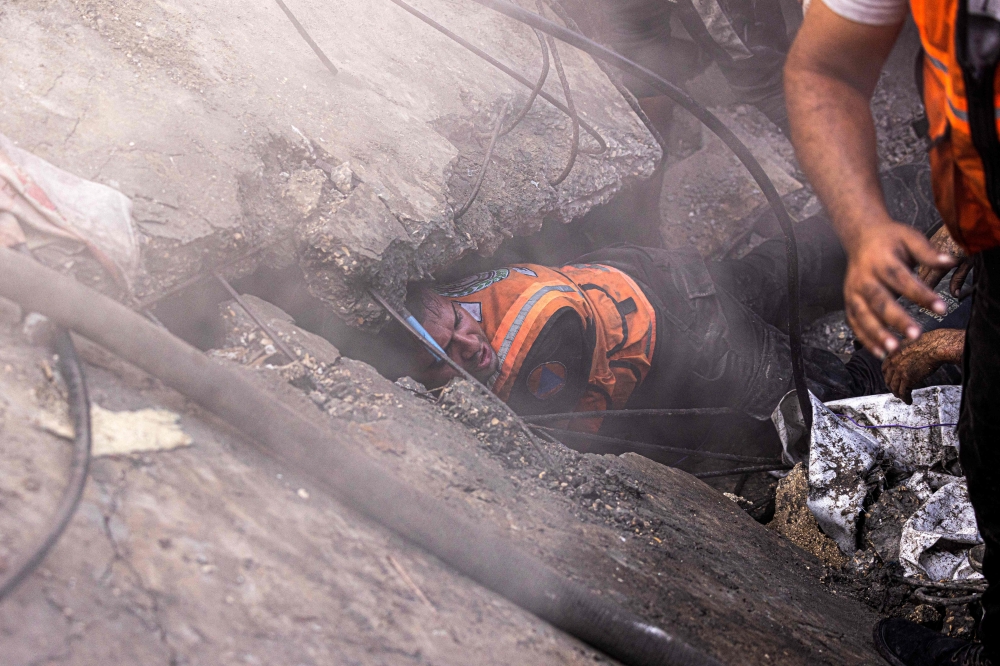 A Palestinian rescuer inspects the rubble of a building in Khan Yunis on November 6, 2023. (Photo by Mahmud Hams / AFP)