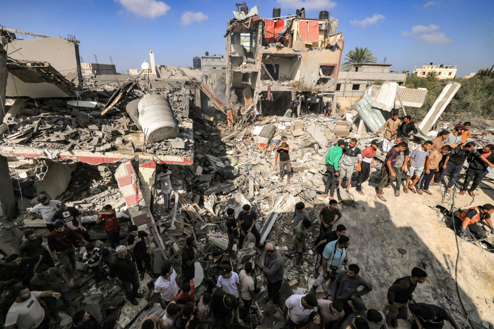 People gather by the rubble of a building that collapsed after Israeli bombardment while searching for survivors and the bodies of victims, in Khan Yunis in the southern Gaza Strip on November 8, 2023. Photo by Mahmud HAMS / AFP