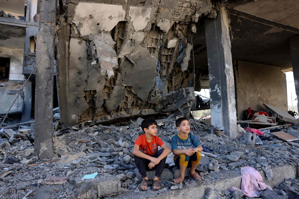 Children sit amid the rubble of a building in the aftermath of an Israeli strike in Rafah in the southern Gaza Strip on November 10, 2023. Photo by Mohammed ABED / AFP