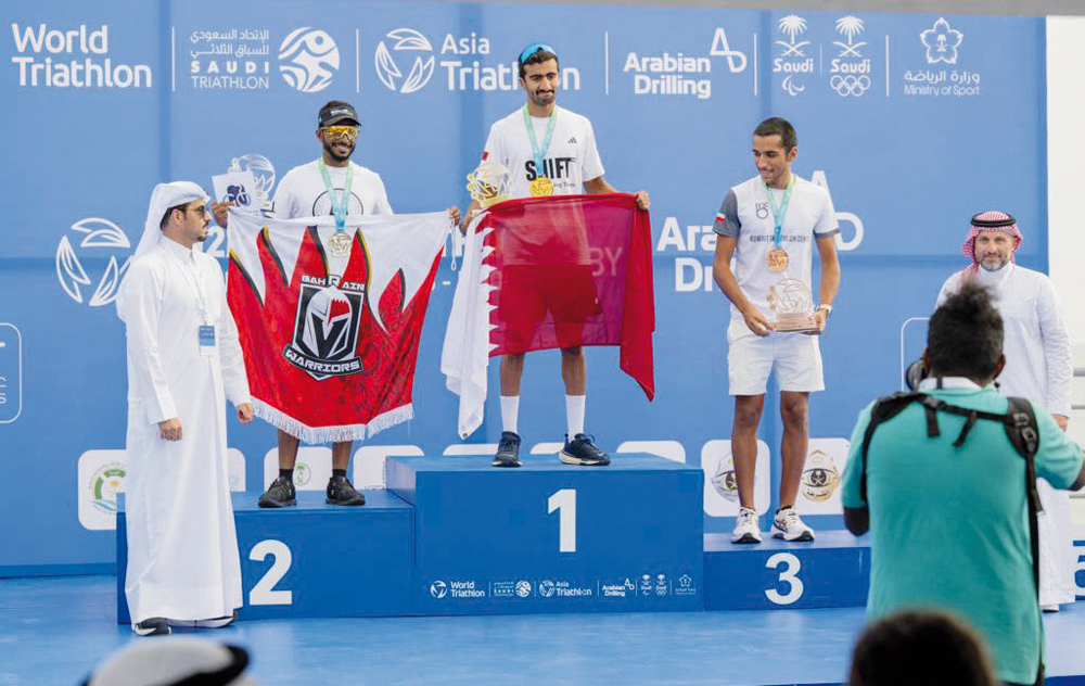 Qatari triathlon team member Tamim Al Kuwari raises the Qatar flag after the Team Relay category competition at the Asia Triathlon Sprint Championships held in Al Khobar, Saudi Arabia. Tamim, Mohamed Al Kuwari and Nayef Al Musallam claimed the top spot in the team rankings. Qatar Cycling and Triathlon Federation President Dr Mohammed bin Jaham Al Kuwari is also seen.