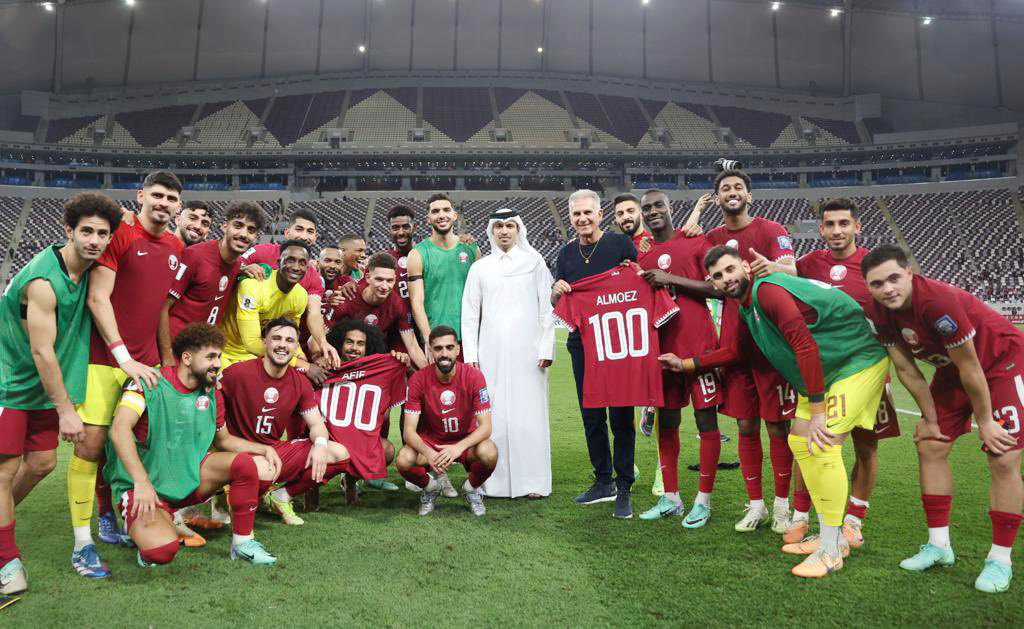 Qatar strikers Almoez Ali (right) and Akram Afif holding jerseys to mark their 100th international-match milestones along with QFA President Jassim Rashid Al Buenain and Qatar head coach Carlos Queiroz besides teammates.