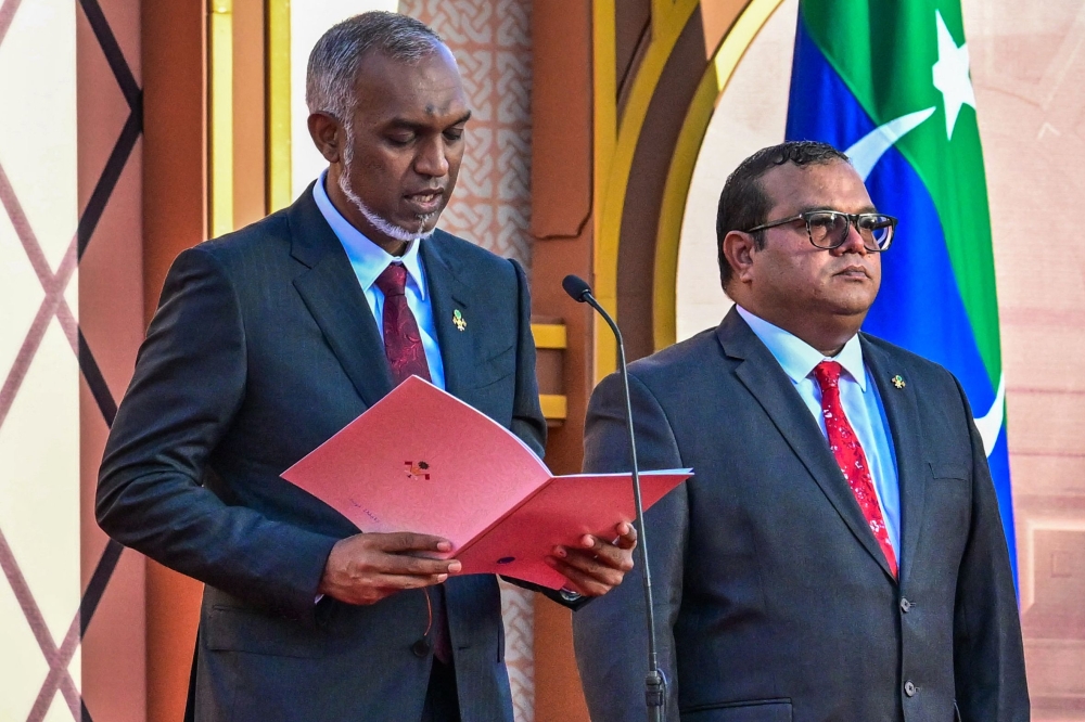 Maldives' president-elect Mohamed Muizzu (L) reads out his oath during his inauguration ceremony in Male on November 17, 2023. (Photo by Ishara S. KODIKARA / AFP)
