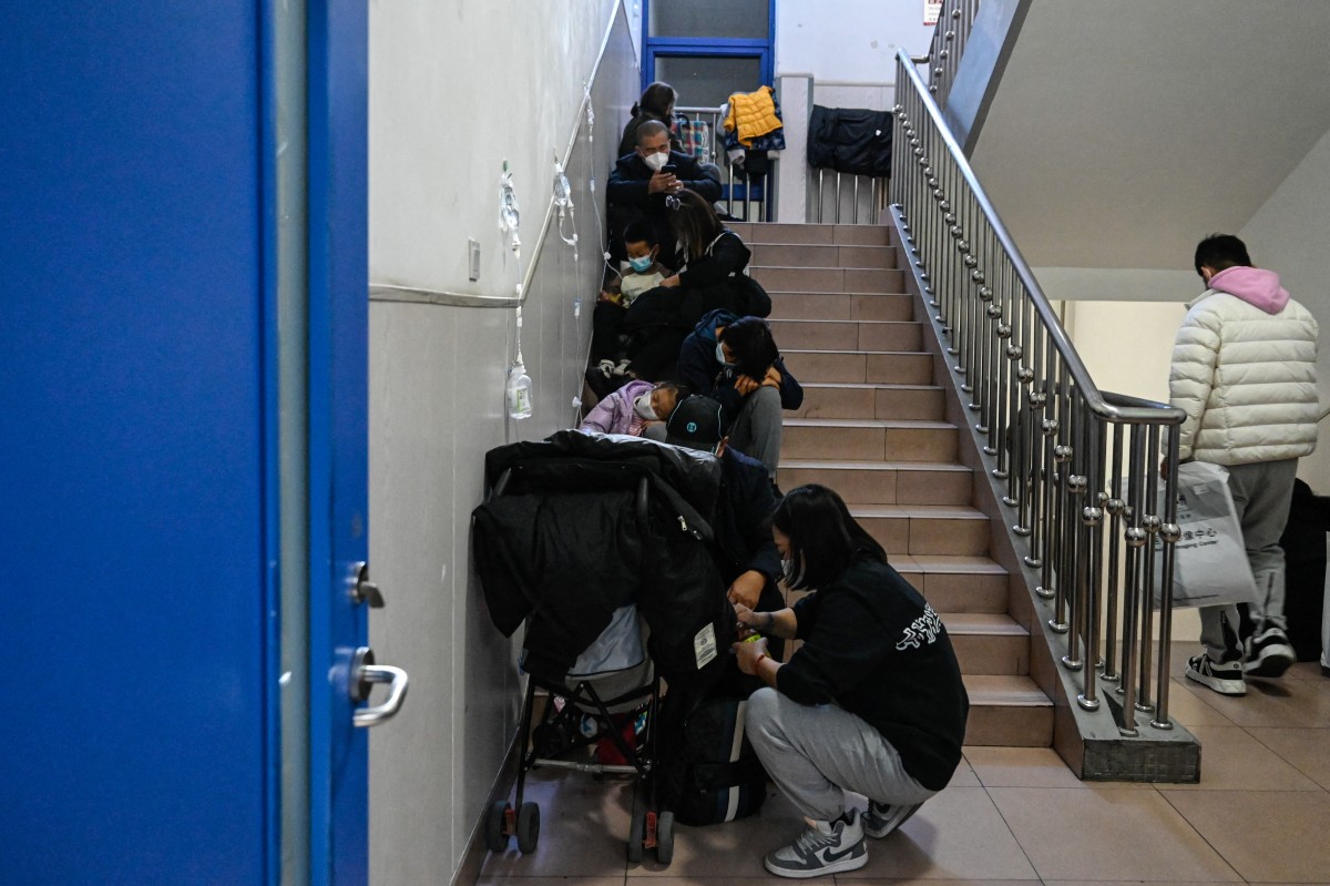 Children receive a drip on the stairs at a children hospital in Beijing on November 23, 2023. (Photo by Jade Gao / AFP)