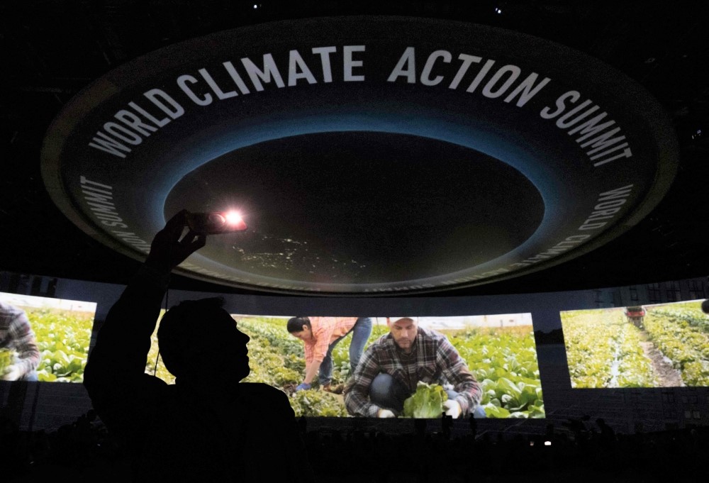 An attendee takes photos during a video presentation as part of the Transforming Food Systems in the Face of Climate Change event on the sidelines of the COP28 climate summit at Dubai Expo on December 1, 2023. (Photo by Saul Loeb / POOL / AFP)